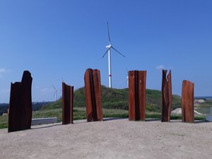 Metalhenge mit Windrädern vor blauem Himmel